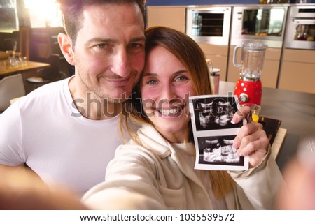 A married couple in love videocall their parents using a tablet, to announce the birth of their son showing the ultrasound. Concept of: family, birth, life, love