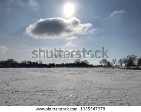 Lake cloud sky cold lake, Scenery sunlight through rain cloud on island and reflection on sea surface, Sun behind gray cloud and snow-covered field - winter view
