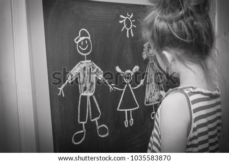 A child draws a family. Day of family and child protection. A little girl draws on a slate.