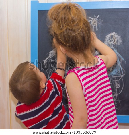 Children draw on the slate. Brother and sister are painting with crayons.