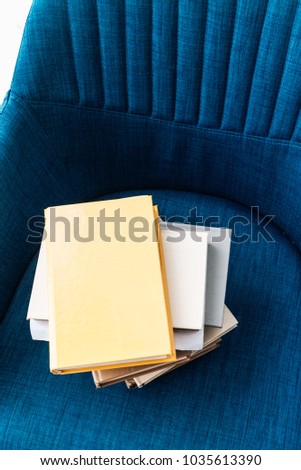 stack of different books on blue armchair 