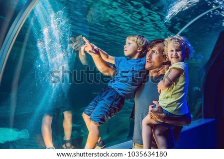 happy family looking at fish in a tunnel aquarium