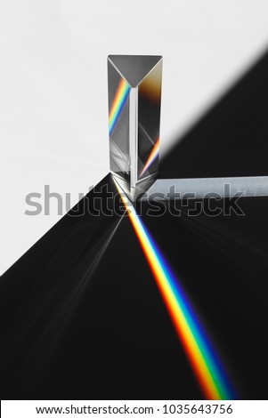A prism dispersing sunlight splitting into a spectrum on a white background.