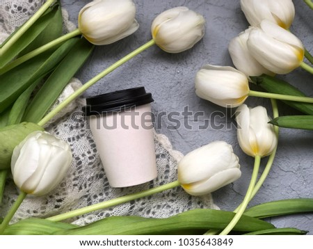 spring white cup to go with white tulips on grey background. spring coffee take away cup