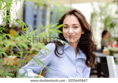Outdoor portrait of young attractive lady sitting in cafe with perfect smile, romantic style
