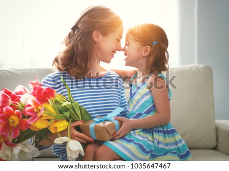 happy mother's day! child daughter congratulates mother and gives a bouquet of flowers to tulips and gift
