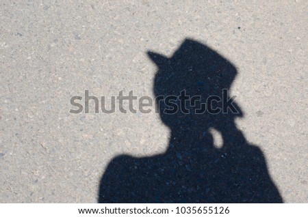 Close Up of a shadow on the sand of a man in a hat