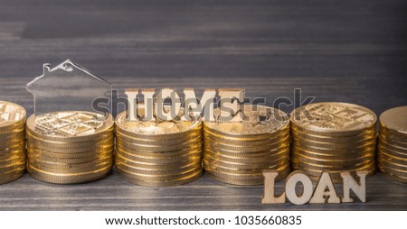 'Home Loan' words with stack of golden coins and house shape sign on dark wooden table top