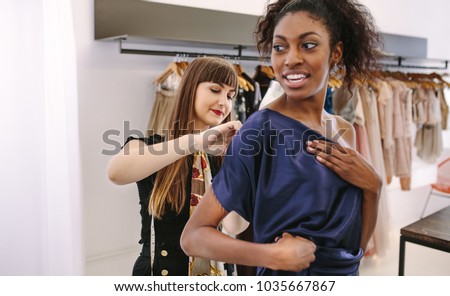 Fashion designer trying new designer clothes on a model. Woman entrepreneur in her cloth shop designing new clothes. Royalty-Free Stock Photo #1035667867