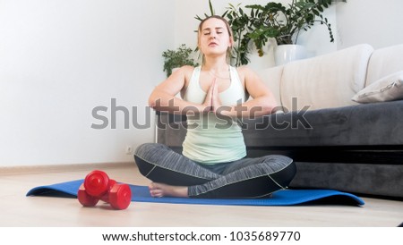 Young woman sitting in yoga pose on floor at home