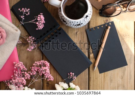 Aramatic coffee in a mug. A white sheet with sheets of black color. Decor of pink flowers on a wooden table and sunglasses. Free space for text. Card.