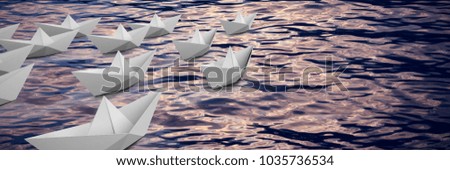 Graphic image of paper boats arranged against scenic view of sea