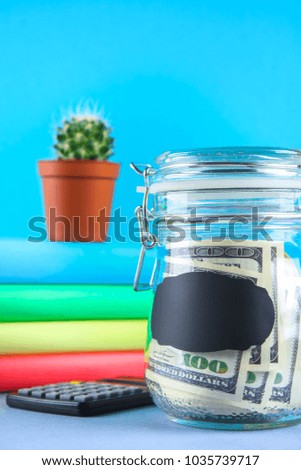 Bank with dollars and calculator, books on a gray background. Finance, moneybox, education