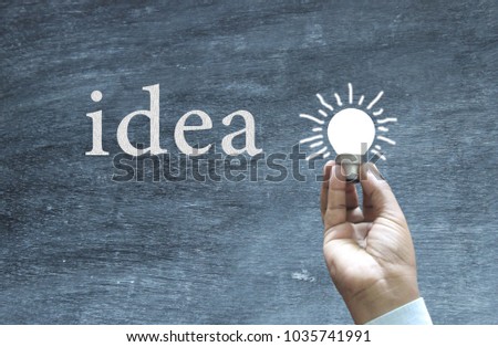 Hand holding bulb and graphically generated text and light rays