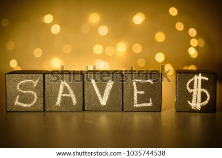 Save $ chalk written on black cubes on blurred bokeh background