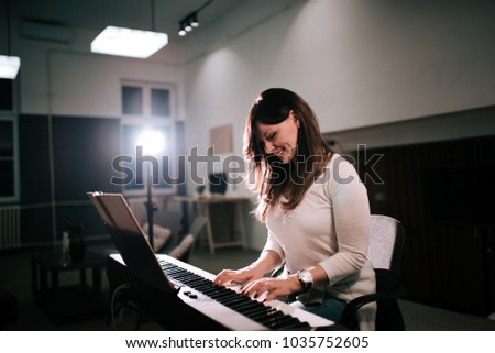 Female composer playing synthesizer piano