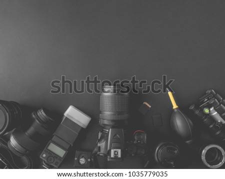 top view of work space photographer with digital camera, flash, cleaning kit, memory card, external harddisk, USB card reader, laptop and camera accessory on black table background with copyspace.