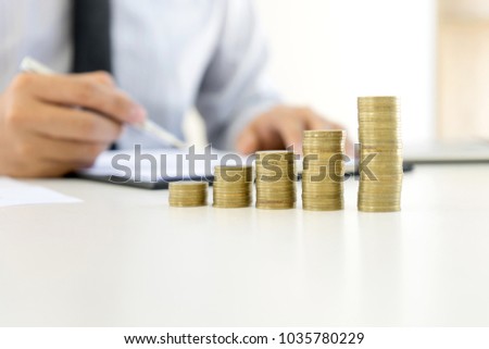 young business man work at the table stack coins on  in the office 