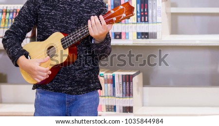 Little child playing ukulele in the library bossanova music in summer time, Cute boy play guitar vintage style, hand picking Guitar ,Ukulele on  the library .