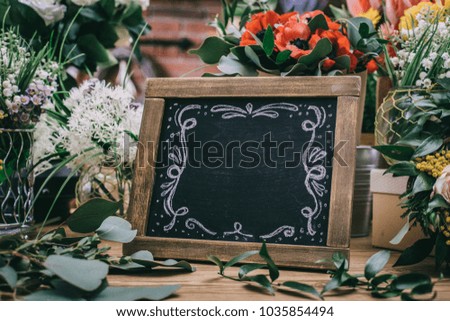 Blank charcoal board among flowers bouquet on florist shop
