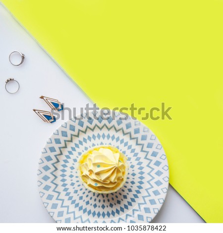 White and yellow picture of cupcake, plate and earrings with empty. Top view. Girls Travel Party Summer Concept. Flat lay. Space for text. Image of birthday party supplies. 