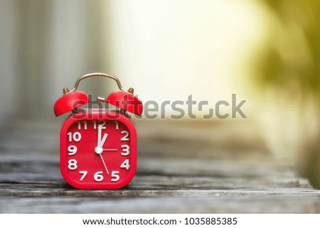 Red alarm clock on the bokeh background. The time shows at one o'clock.