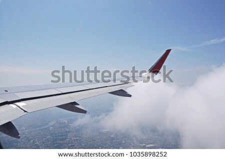 Wing of an airplane flying high in the sky above the clouds.