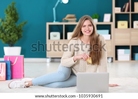 Young woman shopping online with credit card and laptop on floor