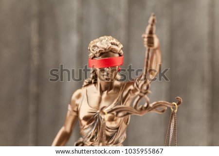 Justitia with blindfold as a justice concept in front of a wood background