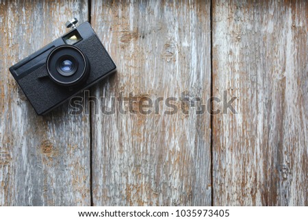 Old photo camera on wooden background.