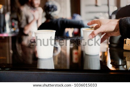 A male hand grabs a take away coffee from a counter in a coffee shop Royalty-Free Stock Photo #1036015033