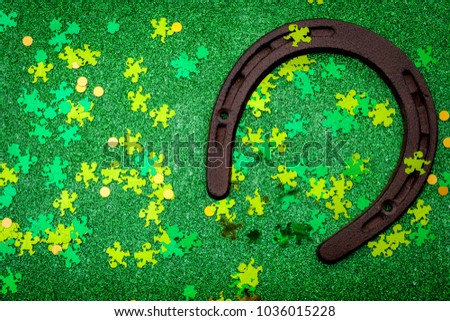 Lucky charm meme, st patricks day and luck of the irish concept with a rusty horseshoe covered party confetti against a sparkly green background