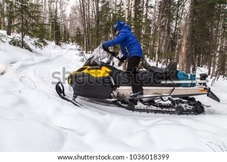 Woman on a snowmobile moving in a winter forest in the mountains of the Southern Urals.