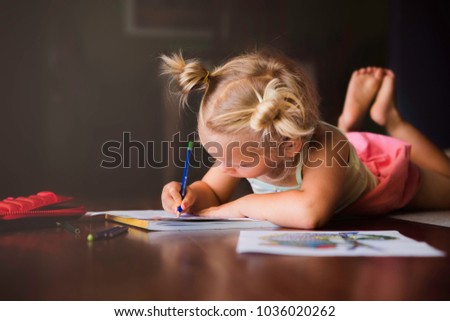 Young girl colouring pictures at home on the floor. 