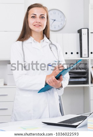Woman is signing patient`s diagnosis in clinic.