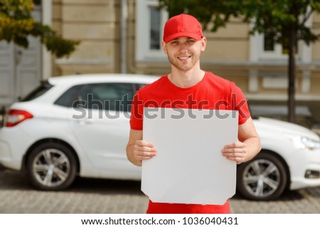 Smiling young courier holding a pizza box. Food delivery concept. Empty space, insert a text or a picture.