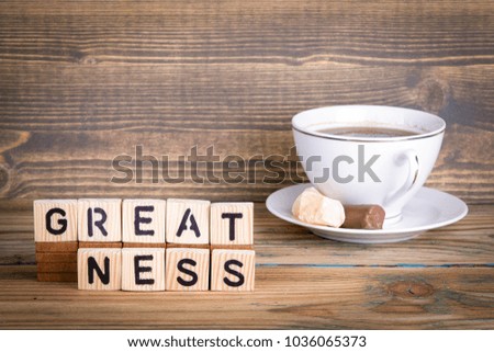 greatness. Wooden letters on the office desk, informative and communication background