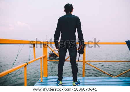 One man Travel around the world with one camera,Man holding camera on hand and standing at sea,man taking photo vintage