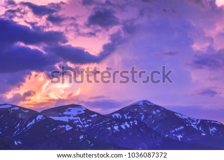 Dramatic skies, snow-capped mountain peaks. Snow-covered mountains. Sunset . Place for text, copy space.