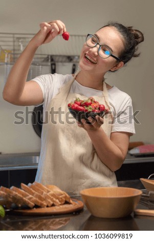 Woman holds fresh strawberries in the kitchen.