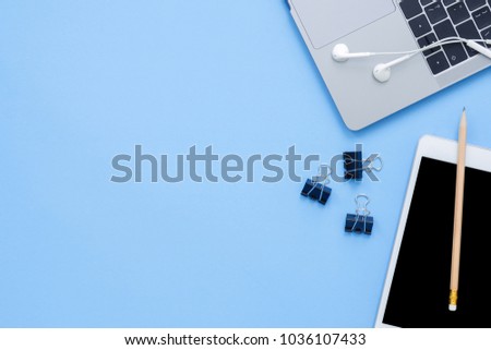 Office desk working space - Flat lay top view mockup photo of a working space with laptop, earphone and mock up tablet on blue pastel background. Pastel blue color copy space working desk concept.