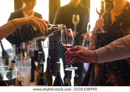 The waitress was pouring a glass of wine. In celebration of the team's success. Royalty-Free Stock Photo #1036108990