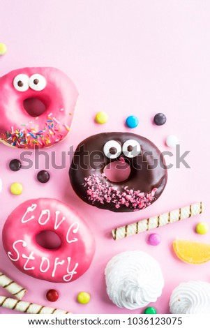 Junk food. Donuts, marmalade, chocolate sticks and balls, and meringue on a pink background. Unhealthy food concept. Top view. Copyspace