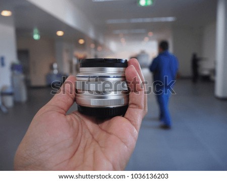 Close-up of woman hand holding a camera lens show in the room office