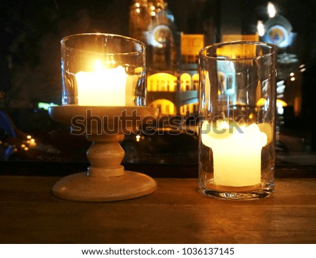 Two burning candles on the windowsill against the background of the night city