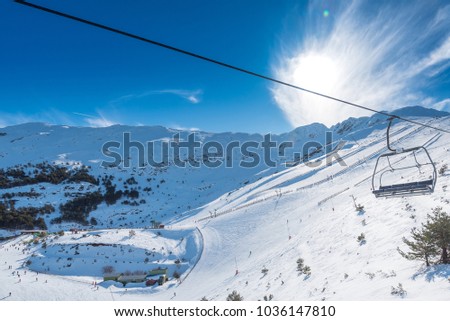 A winter view of a ski resort full of fresh snow taken from the chairlift going up the mountains, in Segovia, Spain