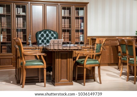 Interior of office room with chairs and laptop on wooden table in classic design