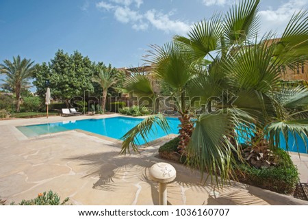 Luxury villa show home exterior at tropical summer holiday resort with swimming pool and garden