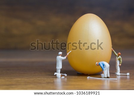 Miniature people :Painter is painting Easter-eggs for Easter day on wooden background