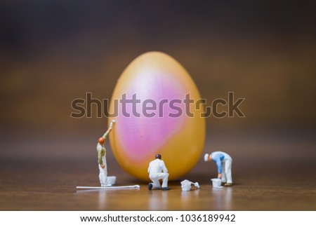 Miniature people :Painter is painting Easter-eggs for Easter day on wooden background